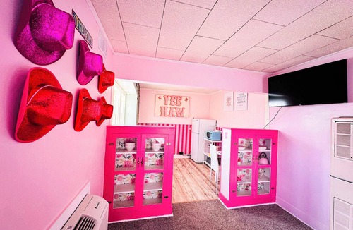 Russell Apartment | Rhinestone Cowgirl is a chic pink-inspired upper-level apartment just blocks from downtown Russell. Enjoy a cozy bedroom, living area with Smart TV, kitchenette, full bath, private balcony, and shared backyard with grill, firepit, and laundry.